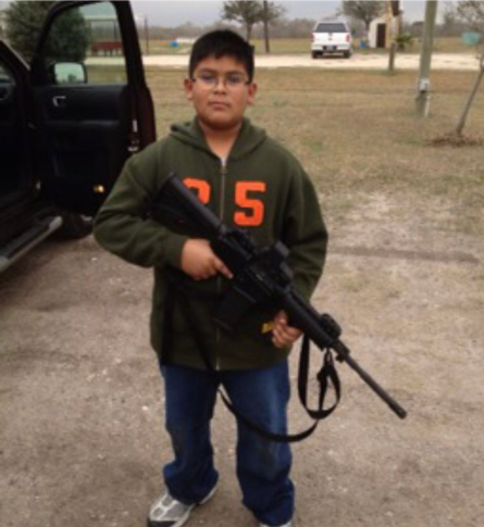 Young boy holding a rifle. Photo by Jacob Benavides.